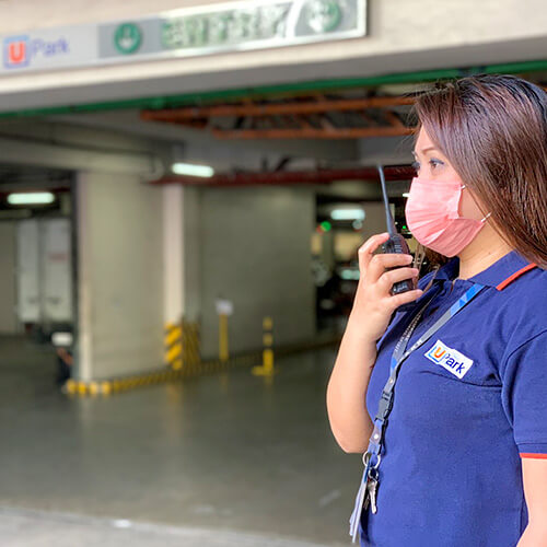 Woman Parking Attendant on Duty communicating using radio by UPark Parking Management